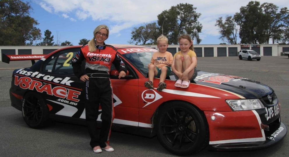 family next to a race car with kids sitting on the bonnet of the car